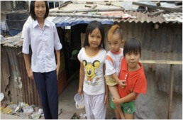 Poor young children and mother outside of dilapidated home. Saigon HCMC Vietnam. Anh Linh School.